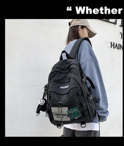 Close-up of black waterproof nylon backpack with cross rope detail and monkey keychain