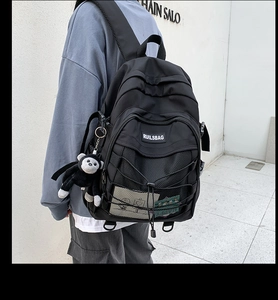 Close-up of black nylon backpack featuring crisscross bungee cords and mesh pockets
