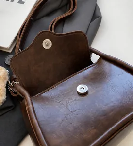 Close-up of retro brown textured leather handbag featuring a round metal magnetic clasp