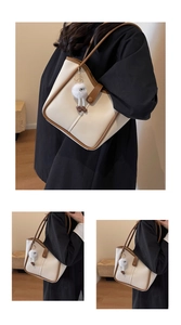 Close-up of cream tote bag with brown trim and cute plush eye charm on the side