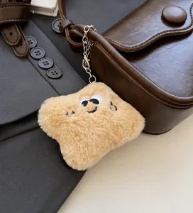 Detail of cute khaki plush toast charm with cartoon face hanging on a brown leather bag