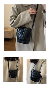 Detail of black quilted bucket bag featuring a diamond pattern and adjustable strap