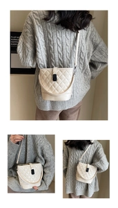 Detail view of quilted white bucket bag with black lock showing crossbody and handheld style
