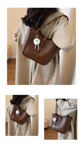 Detail view of coffee brown faux leather tote bag with a white fluffy keychain accessory