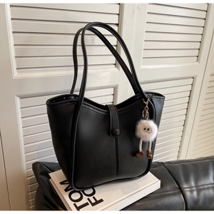 Macro shot of black tote bag with vertical stitching and white plush doll charm