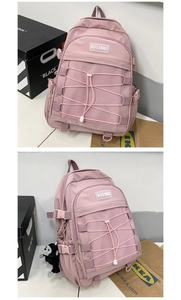 Detailed view of pink school backpack featuring cross-rope mesh pocket and monkey plush charm