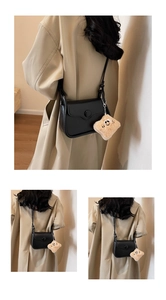 Detail of minimalist black leather crossbody bag with a cute plush smiley face charm