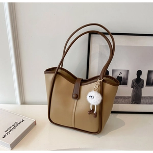 Detail of khaki leather tote bag with brown edge oil and funny white plush monster charm