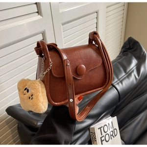 Detail of vintage brown crossbody bag with large round buckle and plush doll charm