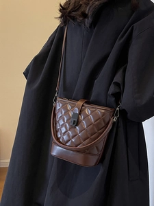 Quilted dark coffee bucket bag with diamond stitching and matte twist lock on black coat