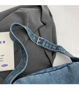 Detail of adjustable denim shoulder strap with metal eyelets and a silver buckle closure