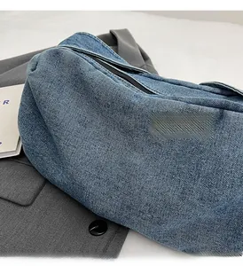 Detailed view of blue denim pillow bag texture on grey suit with metal zipper detail