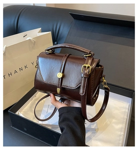Detail view of deep brown vintage leather handbag with antique gold hardware in a gift box