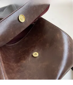 Detailed close-up of the vintage brown leather bag featuring a matte gold magnetic snap closure