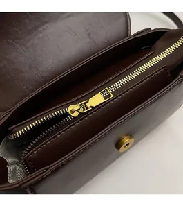 Detail of dark brown leather handbag showing bronze zipper and herringbone lining