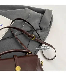 Detail of adjustable leather strap with vintage gold buckle on dark brown crossbody bag