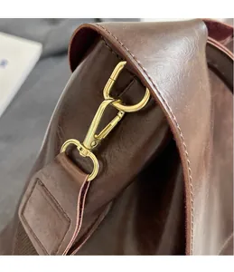 Detail of the golden hardware hook and high-quality stitching on a dark brown leather tote