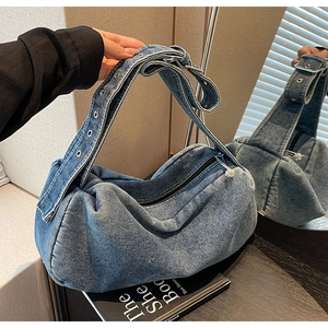 Detailed macro view of retro washed blue denim fabric and metal eyelets on the crescent bag