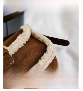 Détail du sac bandoulière en daim marron avec bordure en laine blanche et bandoulière cuir