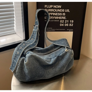Close-up of vintage dark blue washed denim pillow bag with metal eyelets and wide strap