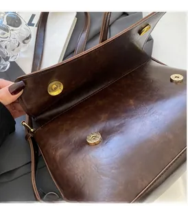 Détail d'un sac en cuir marron vintage brillant avec boucle magnétique dorée ronde