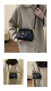 Detail of black leather crossbody bag with a sleek gold rectangular clasp and top handle