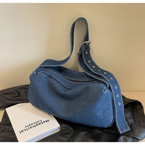 Close-up of blue denim pillow bag featuring silver eyelets and adjustable strap
