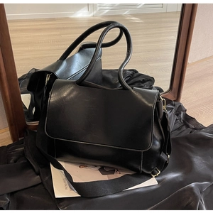 Detail view of black vintage leather tote bag with wide strap and gold hardware