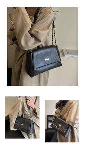 Detail of black leather tote bag with gold metallic buckle and chain shoulder strap