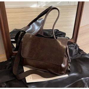 Detail of dark coffee brown faux leather tote bag with wide strap and metallic buckles