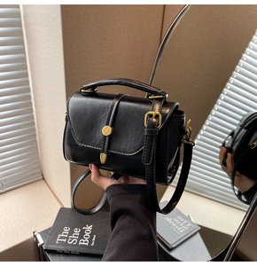 Detail of elegant black PU leather crossbody bag with vintage gold buckle and handle