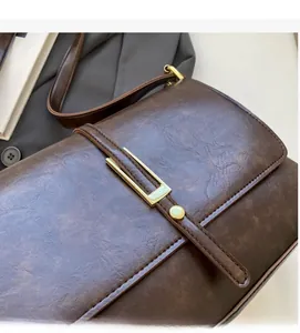Détail du sac à bandoulière vintage marron foncé en similicuir avec boucle dorée chic
