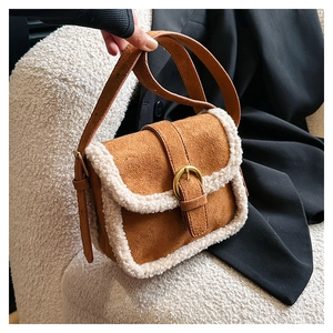 Détail d'un sac bandoulière en daim marron avec garniture en sherpa blanc et boucle dorée