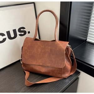 Detailed view of brown PU leather tote with wide fabric strap and top handle design