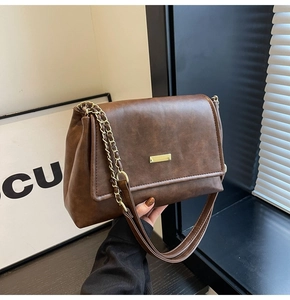 Detail of vintage brown leather bag with golden metal buckle and chain shoulder strap