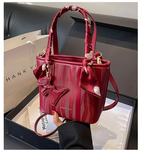 Detail of red wedding bucket bag with wavy texture, heart scarf, and dog charm in a gift box