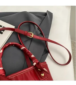 Close-up of red leather wedding bag with woven texture and silk ribbon handle