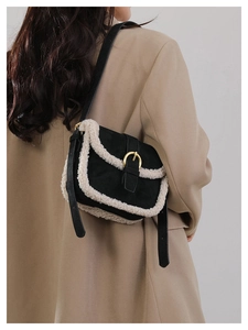 Détail d'un sac bandoulière noir avec bordure en fausse fourrure blanche et boucle dorée