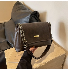 Close-up of vintage dark brown faux leather bag with gold hardware and chain strap