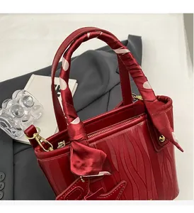 Detail of red leather bucket bag with wave texture and polka dot silk scarf handle