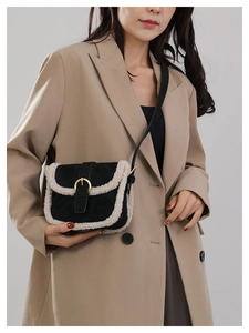 Détail du sac bandoulière noir avec bordure en fourrure et boucle dorée sur manteau