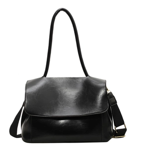 Large black leather tote bag with wide crossbody strap and golden hardware accents