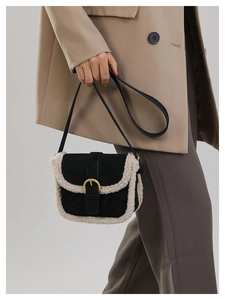 Détail de la bandoulière noire avec bordure en molleton blanc cassé et boucle en métal doré