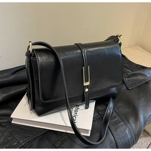 Détail d'un sac à bandoulière vintage en cuir noir avec une boucle en métal doré poli