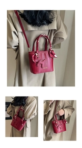 Detail of red bucket bag with 3D puppy charm and polka dot scarf wrapped handle