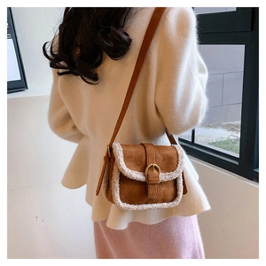 Gros plan d'un sac bandoulière en daim marron avec bordure en peluche et boucle dorée