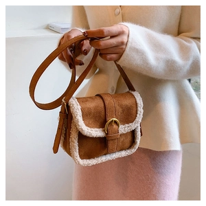 Détail du sac bandoulière vintage en daim marron avec bordure en fourrure blanche et boucle métal