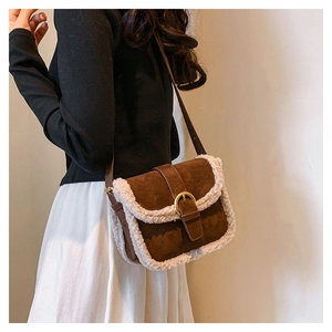 Détail d'un sac bandoulière en daim marron avec bordure en fourrure crème et boucle dorée