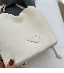 Detail shot of the triangular logo plaque and white textured leather on a chain bucket bag