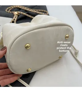 Detail view of the white bucket bag bottom with four gold metal protective studs